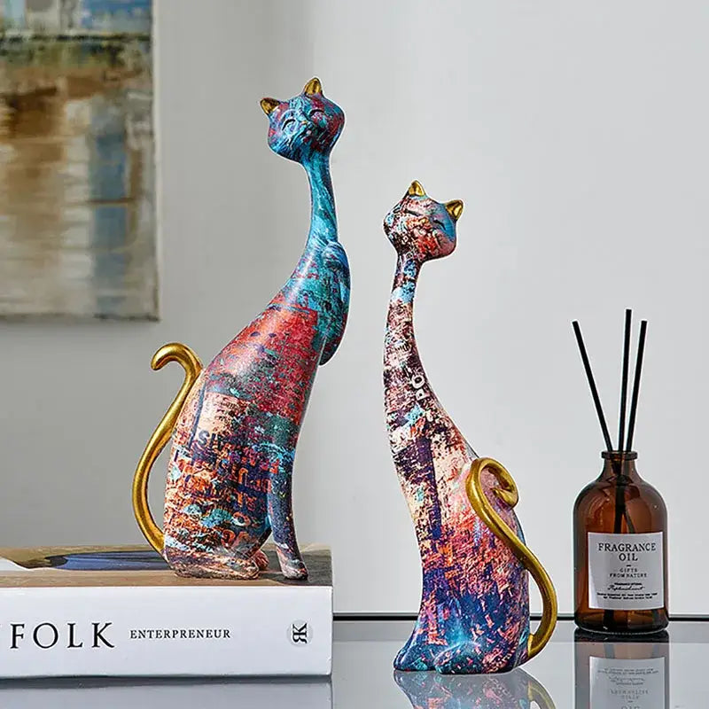 Two stylized cat lovers resin figurines with vibrant blue red purple paint splatter and gold accents for decorbites cat lovers