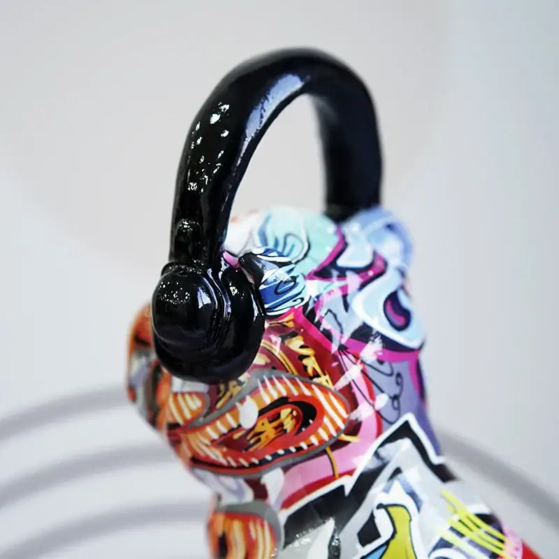 A glossy black resin handle with a curved finish atop a vibrant graffiti painted bulldog headphone figurine