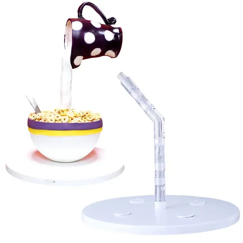A whimsical white polka dot ceramic mug pours milk beside a gravity defying white cake stand support structure