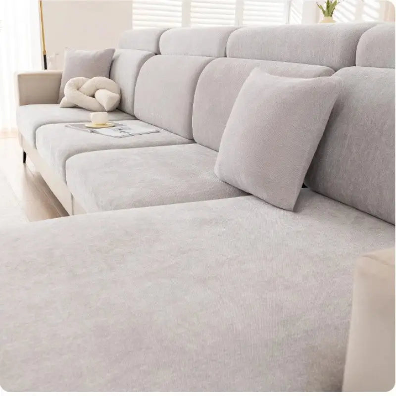 A modern light gray sectional sofa with soft textured fabric and matching pillows featuring a gray and beige chenille sofa cover