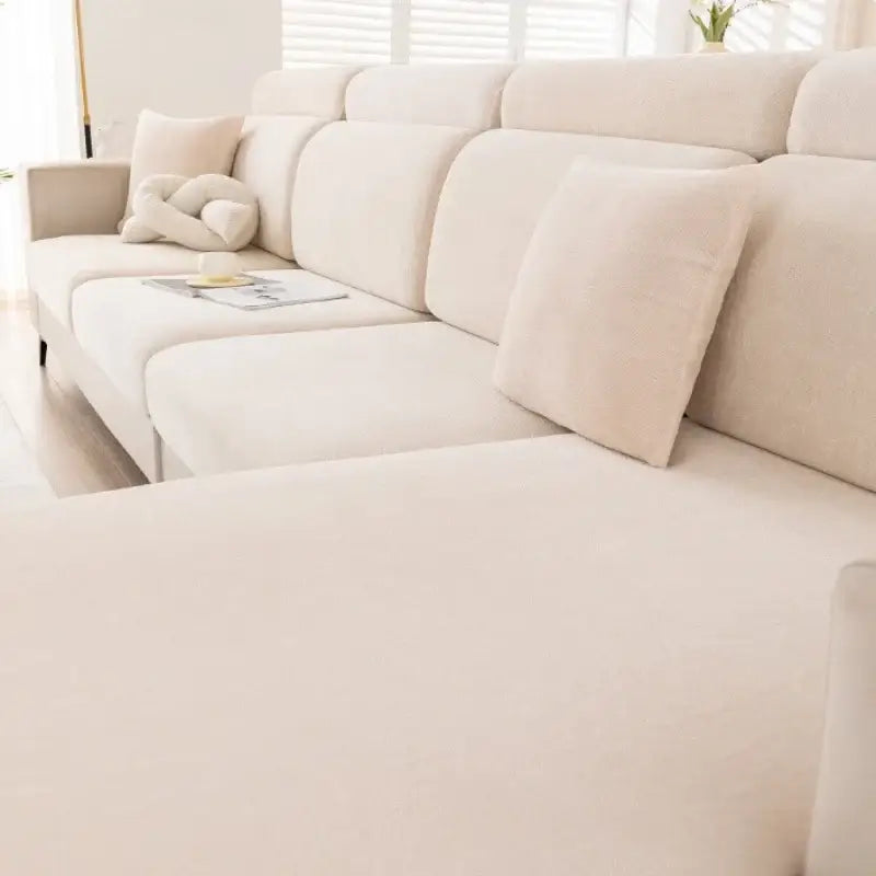 Beige sectional sofa with plush segmented cushions covered by gray and beige chenille universal sofa cover in living room