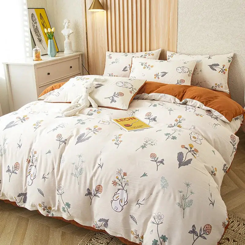 Cream-colored bedding set with delicate floral and bunny pattern accented by warm orange trim and green leaf print