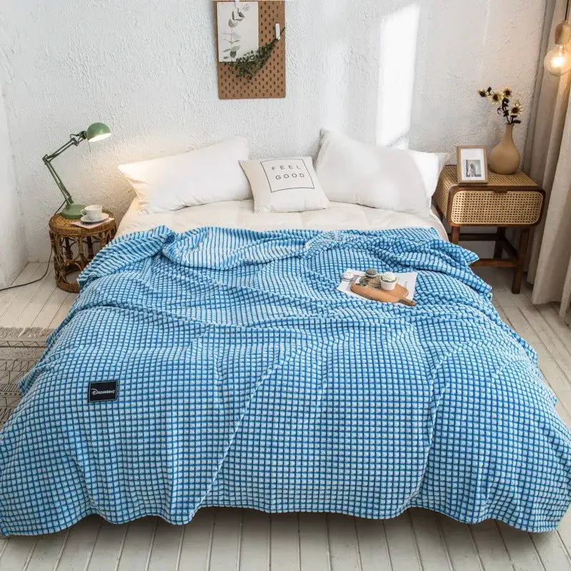 Blue checkered quilted bed blanket with soft textured surface and black brand tag for gray plaid coral fleece use