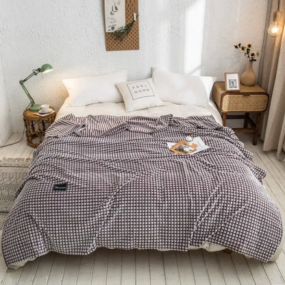 A cozy gray plaid coral fleece bed blanket with a soft textured fabric ideal for bedroom use