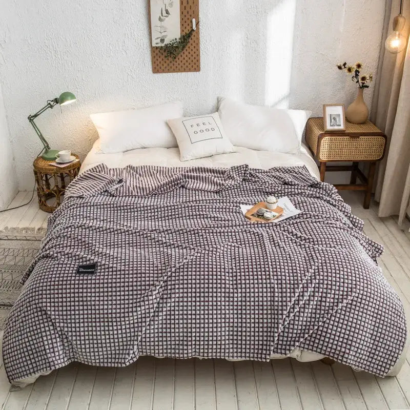A cozy gray plaid coral fleece bed blanket with a soft textured fabric ideal for bedroom use