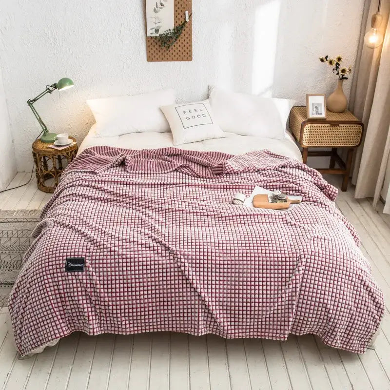 Cozy pink and white checkered fleece blanket with soft texture alongside gray plaid coral fleece bed blanket for bedroom use