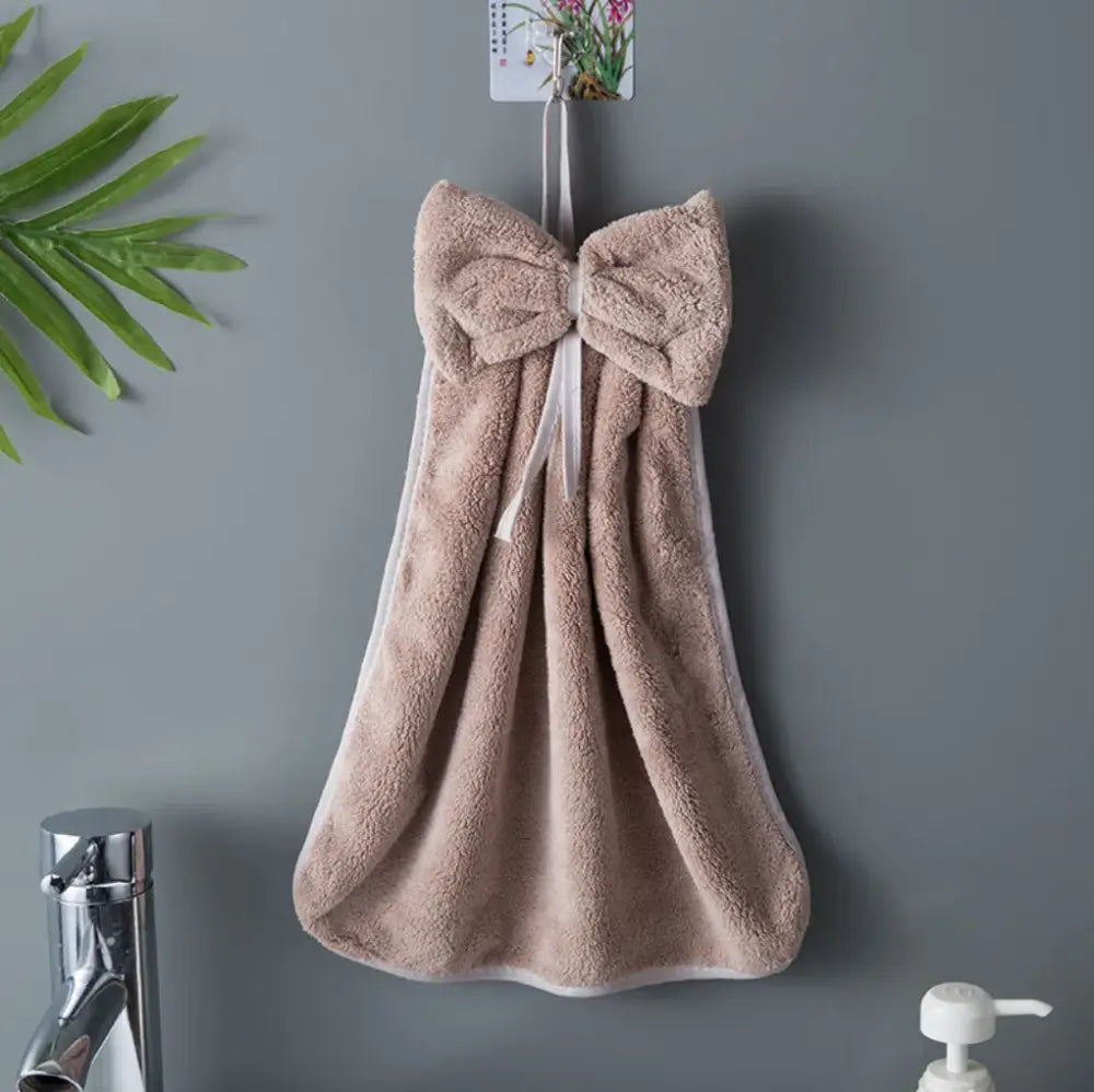 A plush beige hand towel with white trim and a large bowknot coral velvet accent from decorbites bowknot coral collection
