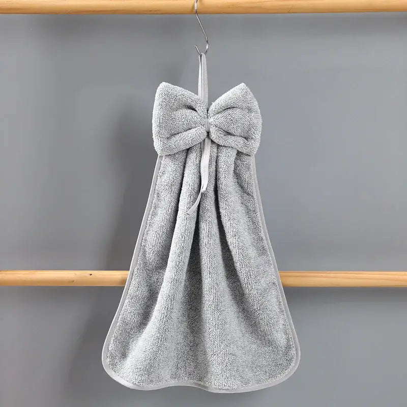 Gray terry cloth hand towels with a plush bowknot coral velvet design hanging on a hook by decorbites