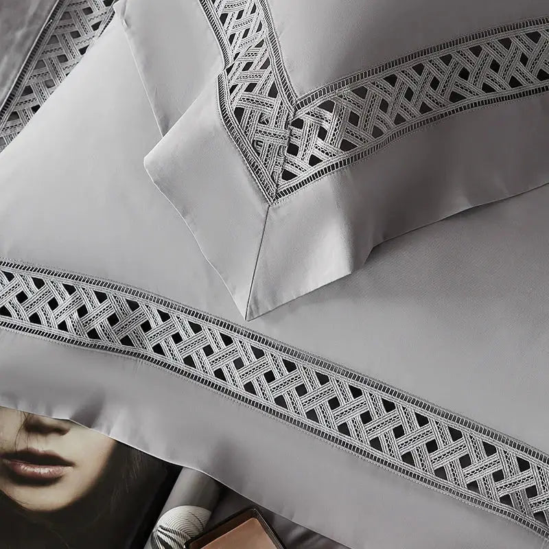 Gray satin pillowcases with intricate black geometric embroidery on edges in egyptian cotton hotel bedding set