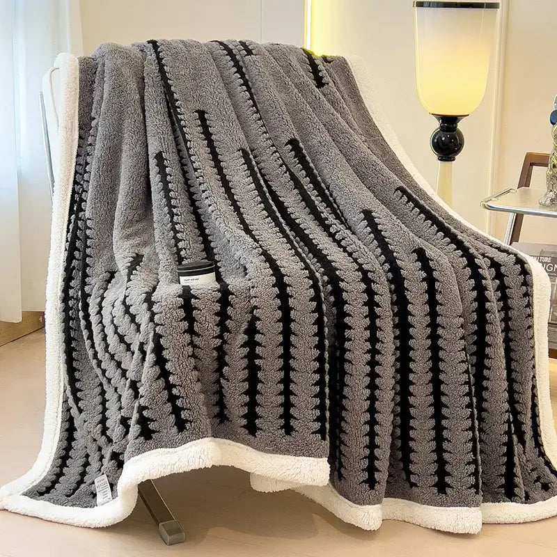 Gray and black decorbites jacquard blanket with a textured striped pattern and white fleece border made of thick lamb wool