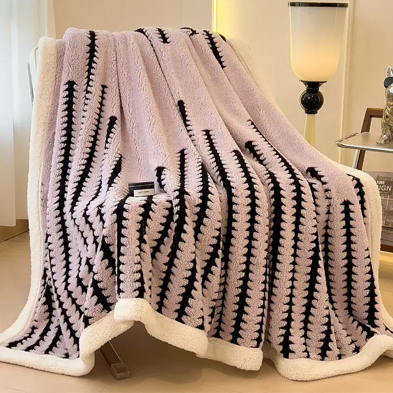 A plush pink and black striped decorbites jacquard blanket with a cozy white fleece border for living room use