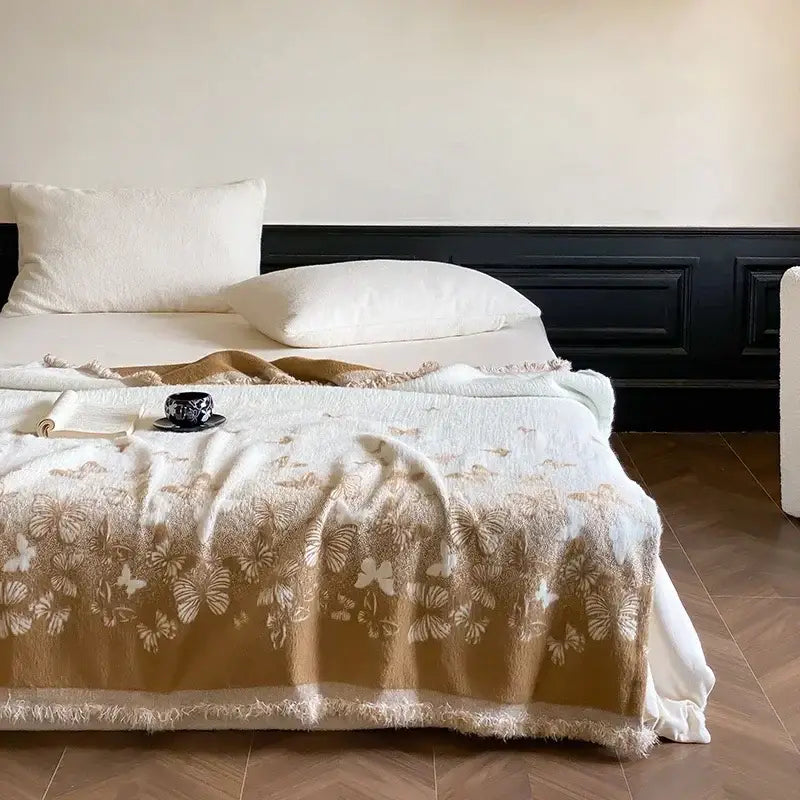 A soft cream-colored decorbites butterfly jacquard imitation mink fur blanket with delicate beige and white butterfly patterns