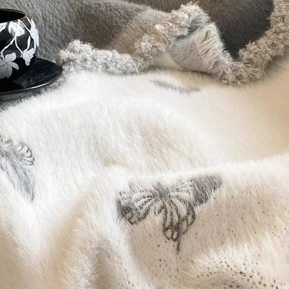 A soft off-white decorbites butterfly jacquard imitation mink fur blanket with subtle gray butterfly embroidery for bedroom decor