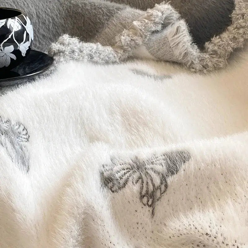A soft off-white decorbites butterfly jacquard imitation mink fur blanket with subtle gray butterfly embroidery for bedroom decor