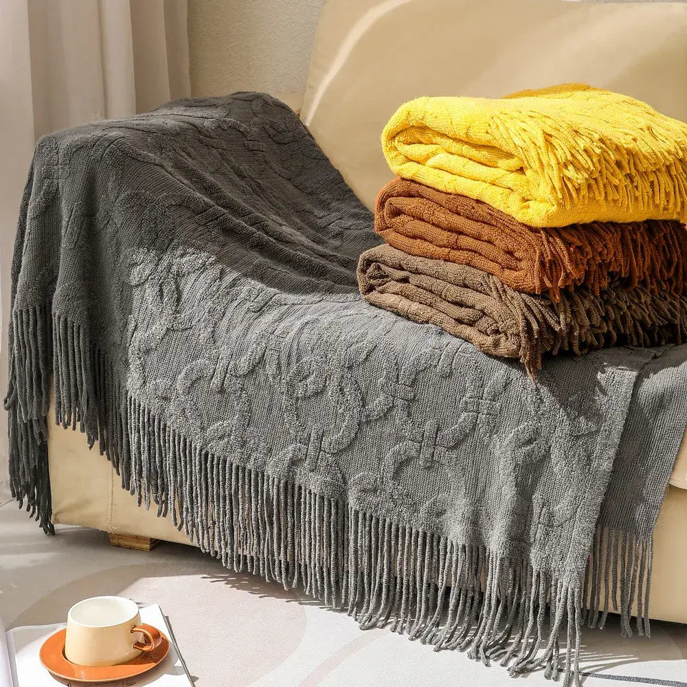 Gray cable knit blanket sofa throw with textured cable pattern and fringe displayed with decorbites knit blanket stack