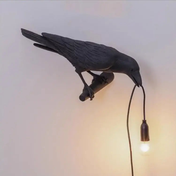 Black crow-shaped wall lamp with textured feathers and hanging bulb featuring decorbites lively bird resin design