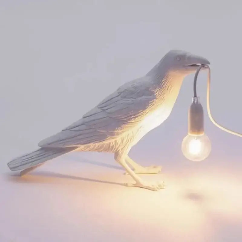 Gray ceramic lively bird resin table lamp with glowing bulb held in beak for bedroom decorbites lively bird decor