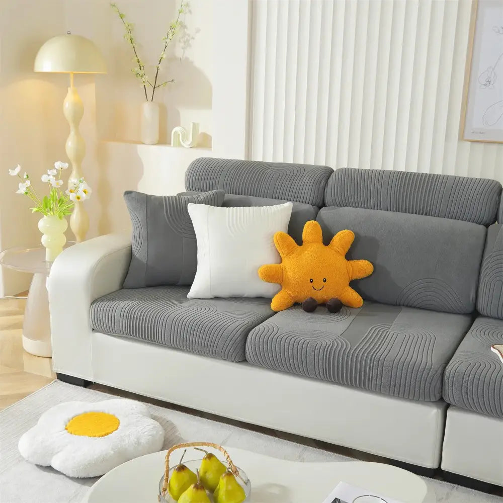 A cheerful orange plush sun pillow with smiling face on a gray circular textured polar fleece modular sofas cover