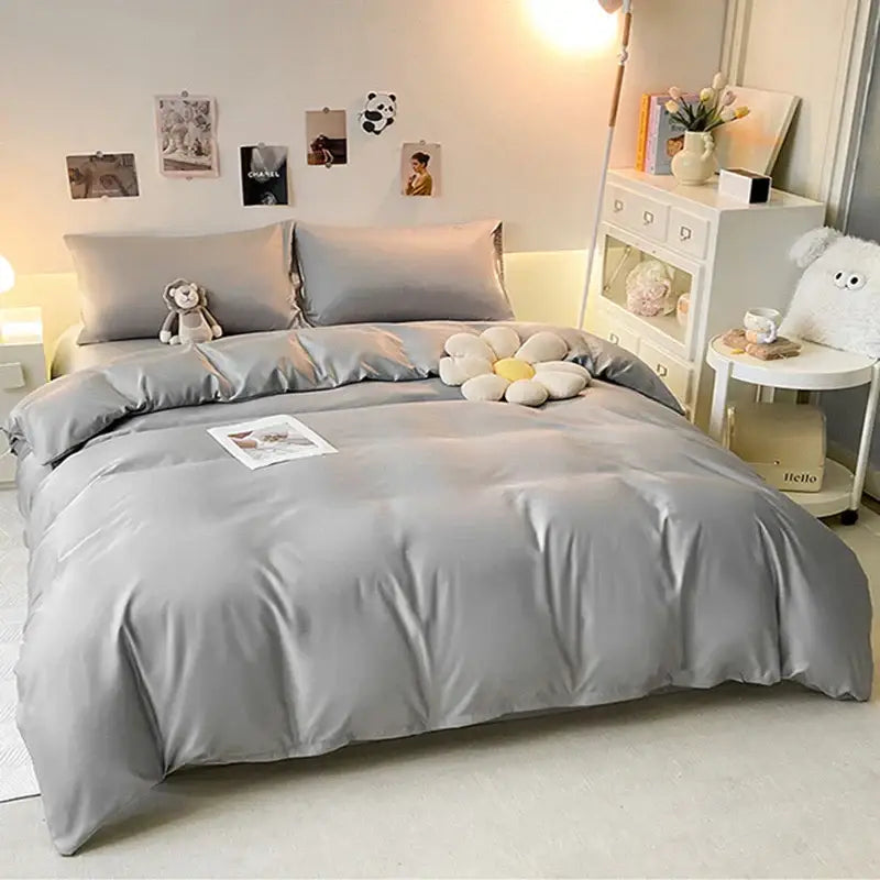 A soft gray double color blocked ice silk bedding set with matching pillowcases and a plush white flower cushion