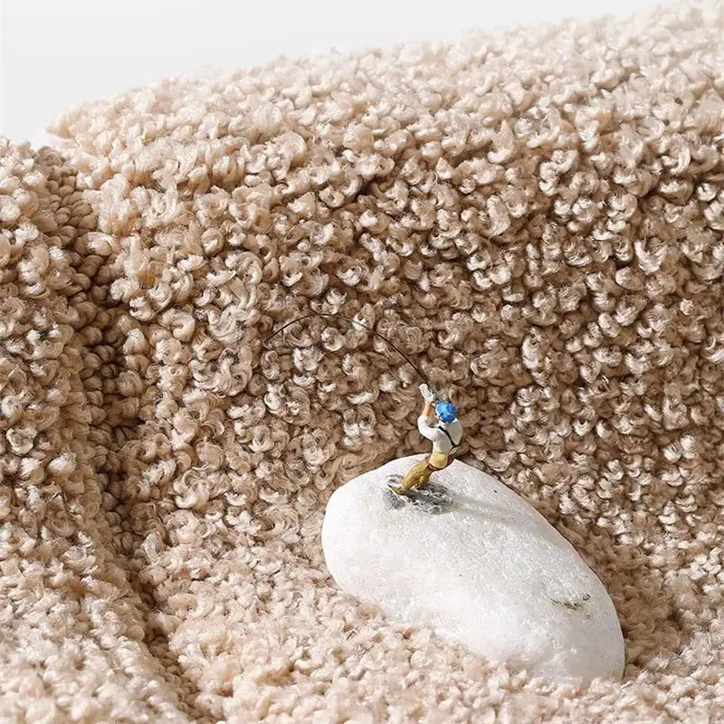 Miniature fisherman figurine on a smooth white stone displayed on a gray geometric flocked bath mat decorbites rug