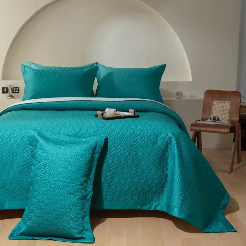 Teal quilted bedspread set with subtle geometric pattern and matching pillows made from egyptian cotton