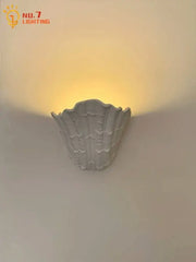 Gray gypsum shell led wall lamp with textured ridged surface designed as a shell-shaped bedroom sconce