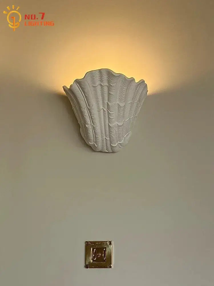 White gypsum shell led wall lamp with a textured ridged surface designed as a bedroom sconce