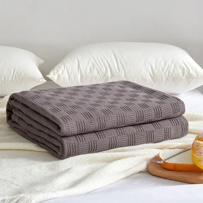 Folded gray knitted throw blanket with textured diamond pattern featured in decorbites cotton waffle towel quilt collection