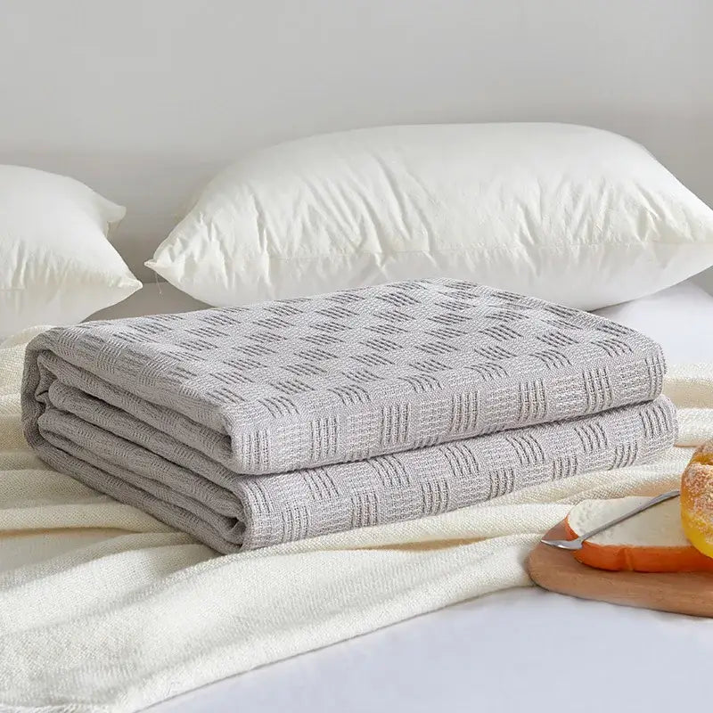 Folded gray herringbone cotton waffle towel quilt with subtle geometric weave pattern for bedroom or office decorbites cotton waffle
