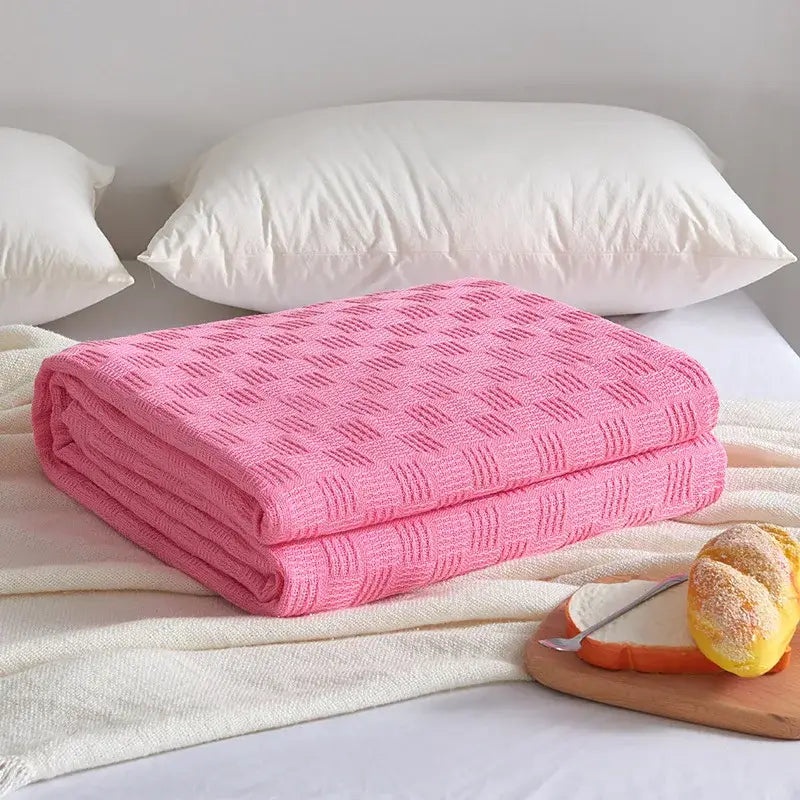 A soft pink knitted blanket with a textured pattern folded on a bed for decorbites cotton waffle towel quilt use
