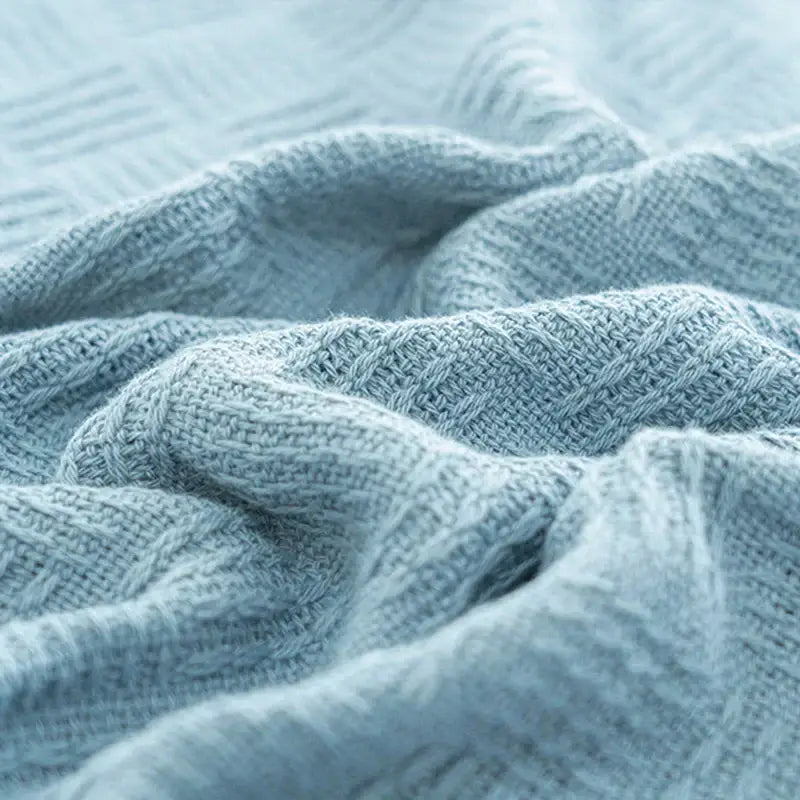 A soft light blue knitted decorbites cotton waffle towel quilt with textured weave for bedroom or office decor