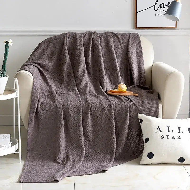 Gray herringbone cotton waffle towel quilt draped over armchair featuring soft textured cotton waffle decorbites cotton waffle design