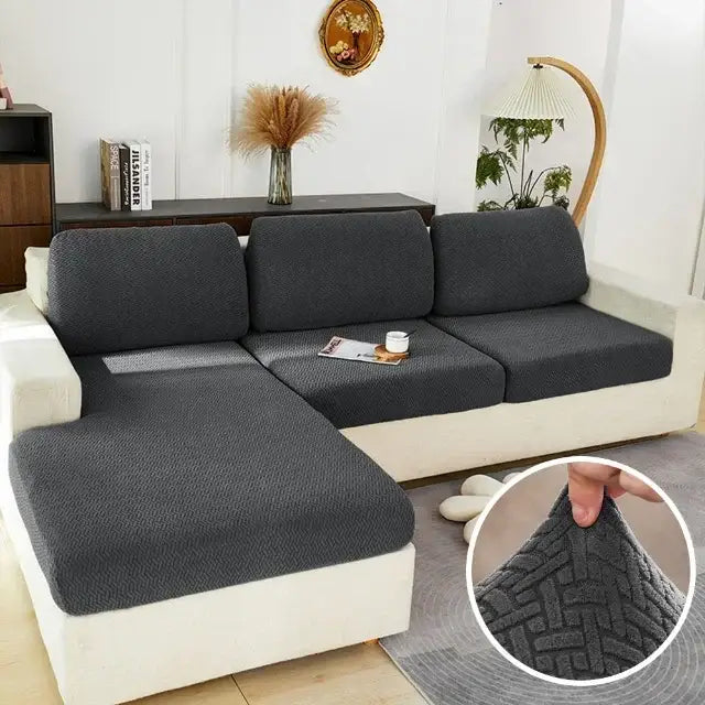 Gray herringbone stretch sofa seat cover in dark gray textured fabric with a snug fit over white sectional sofa
