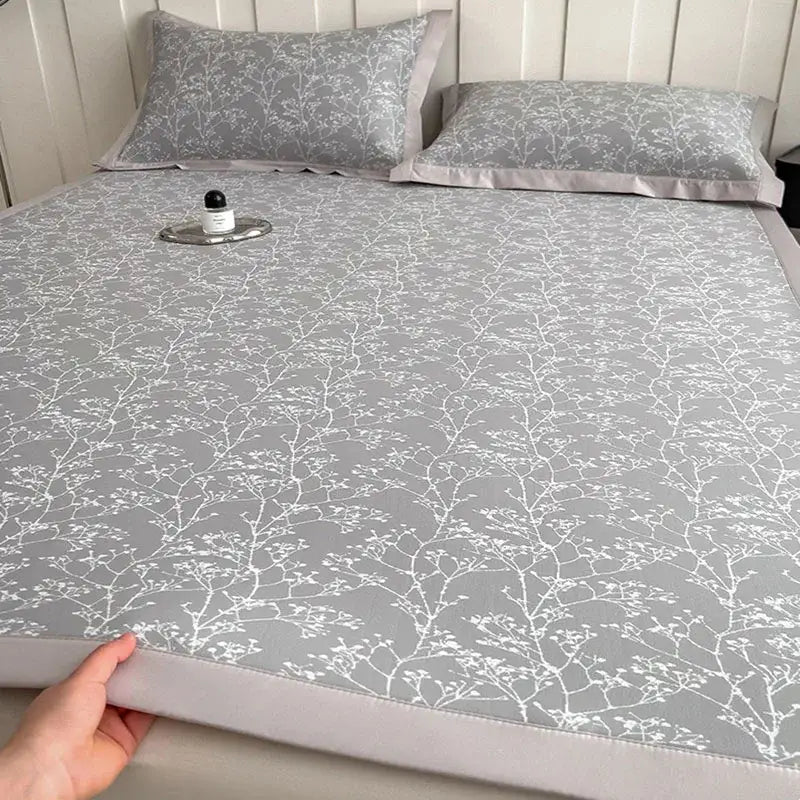 Gray cooling mattress pad with lavender branch pattern and satin border in a bed mat set for bedroom use