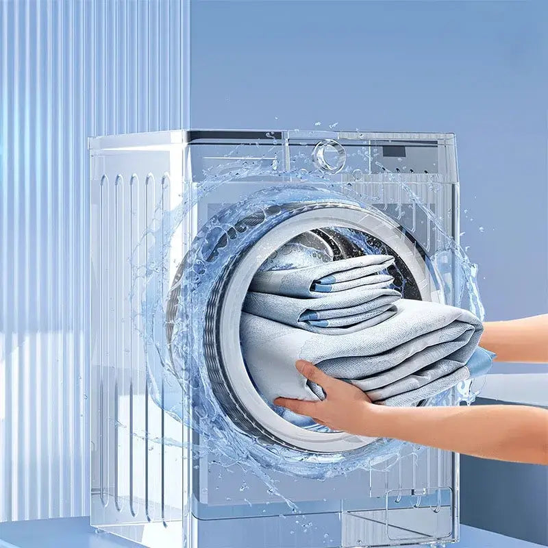 Transparent front-loading washing machine with visible water splashes shown alongside gray and lavender branch pattern bed mat set