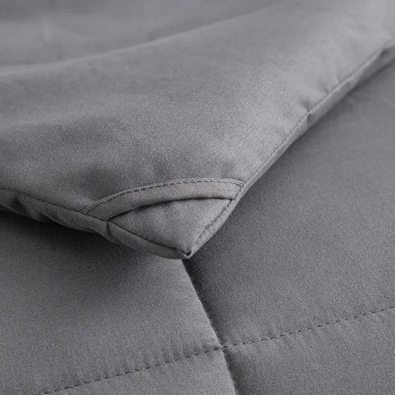 Gray king size quilted comforter with soft textured fabric and neat stitching for a plush bedroom blanket