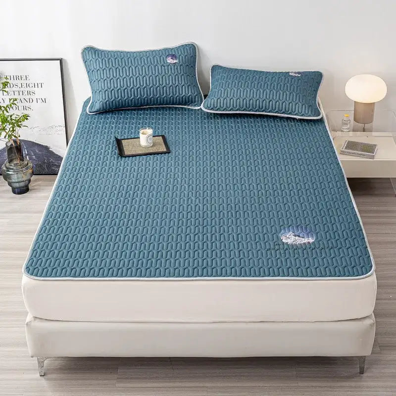 Teal quilted cooling latex bed mat with white piping and subtle embroidered cloud motifs in a bed mat set