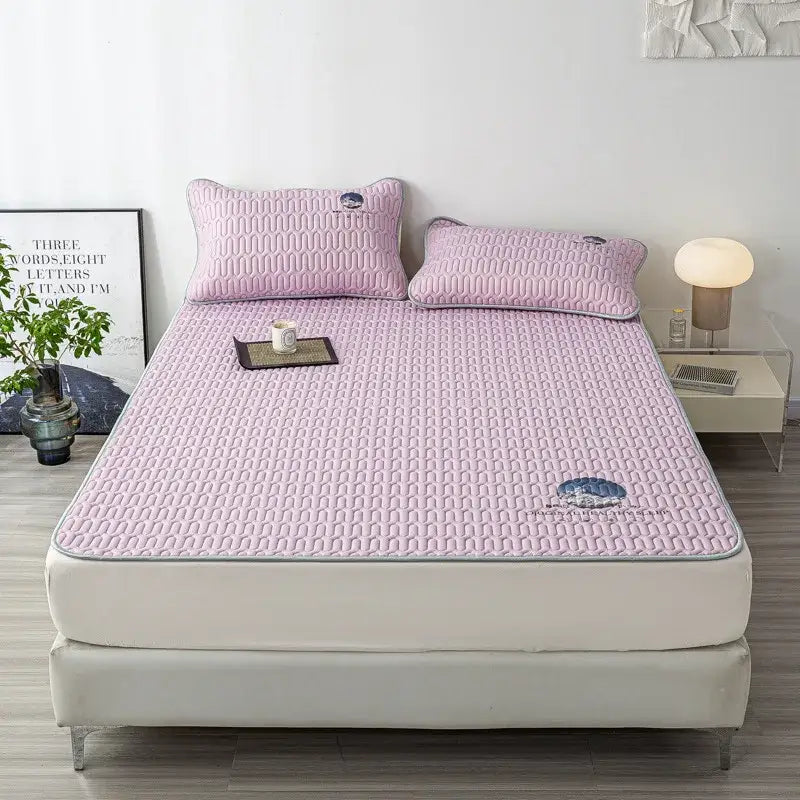 Pink quilted latex bed mat with subtle geometric pattern and blue cloud embroidery in a bed mat set
