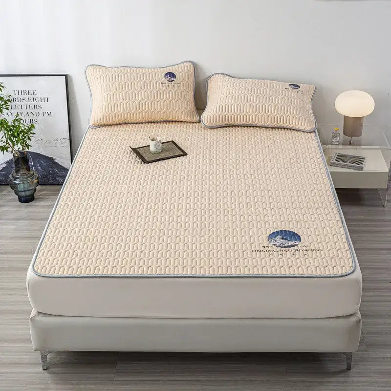Beige quilted latex bed mat with gray piping and blue mountain embroidery in a gray bed mat set