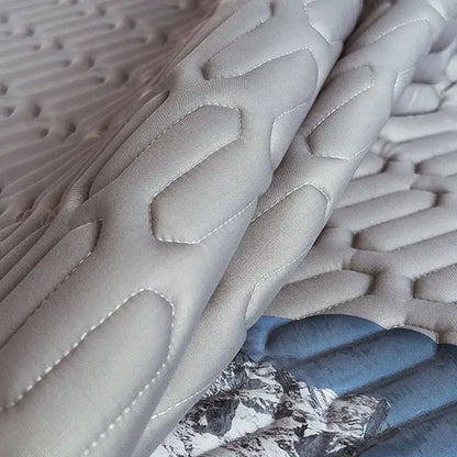 Gray quilted latex bed mat set with textured honeycomb pattern and white stitching for enhanced bedroom mattress comfort
