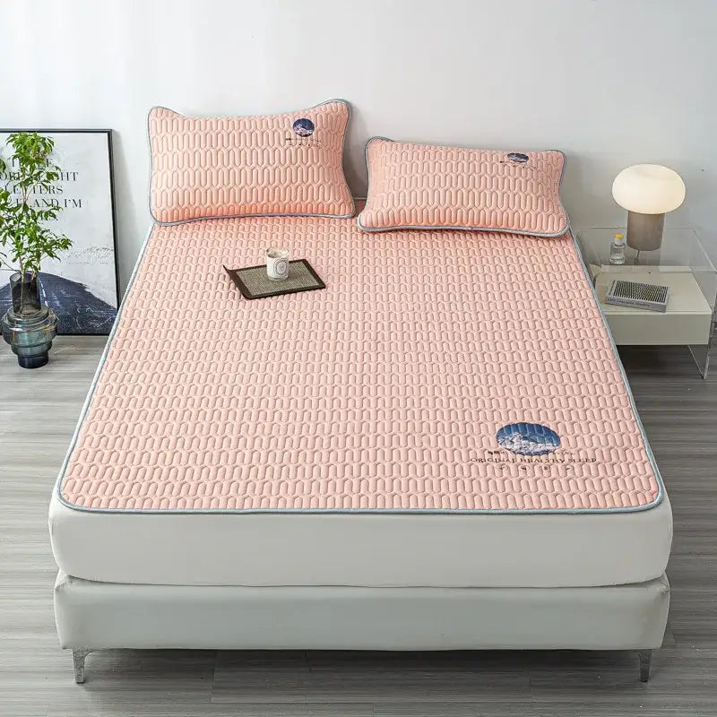 Pink quilted latex bed mat set with subtle texture gray piping and blue embroidered cloud designs on pillows and corner