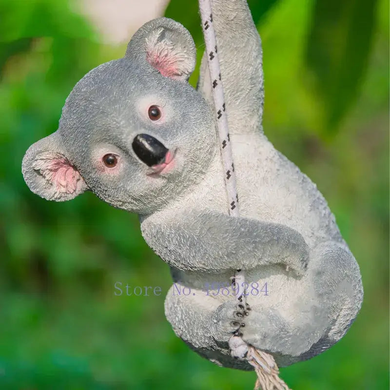 Gray resin cartoon koala garden sculpture with pink ears and black nose hanging from a rope outdoor decorbites cartoon koala