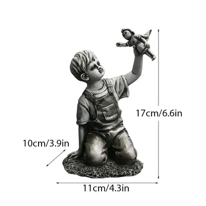 Gray resin super nurse angel boy statue of a kneeling boy in overalls holding a doll for living room decor