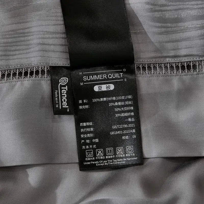 Black fabric tag on gray ruched summer quilt set with tencel material and care details for bedroom bedding summer quilt set