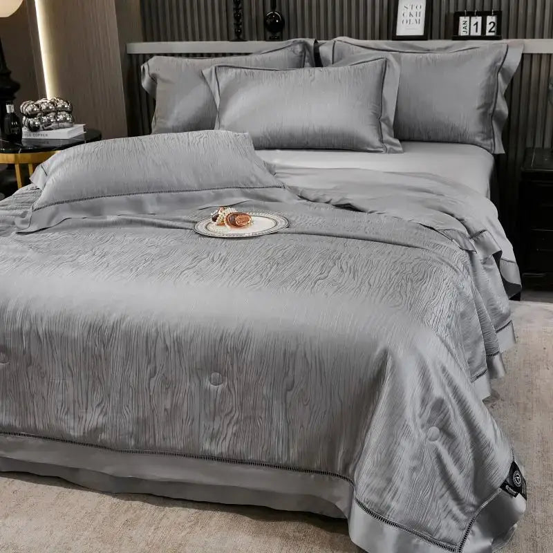 Gray ruched summer quilt set with gray satin-like duvet cover featuring subtle wood grain texture and elegant ruffled edges
