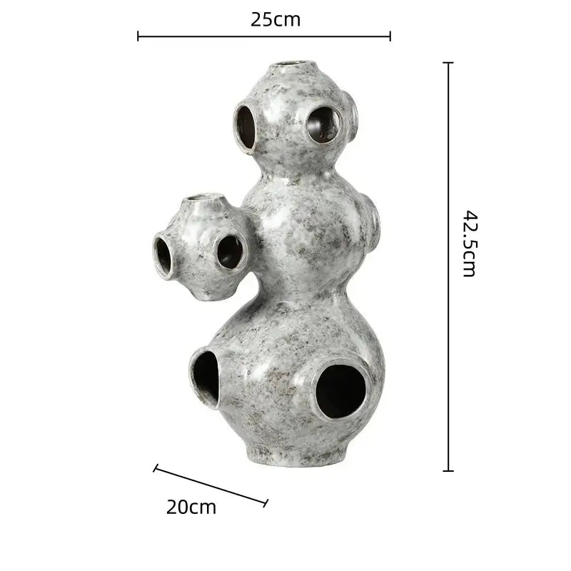 Gray speckled ceramic ornament with multiple rounded sections and circular openings abstract planet decorbites sculpture