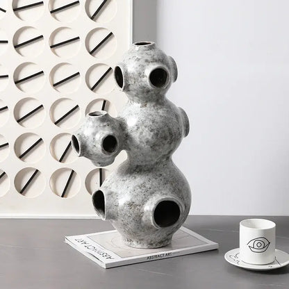 Gray speckled ceramic ornament with rounded segments and circular openings abstract planet decorbites sculpture