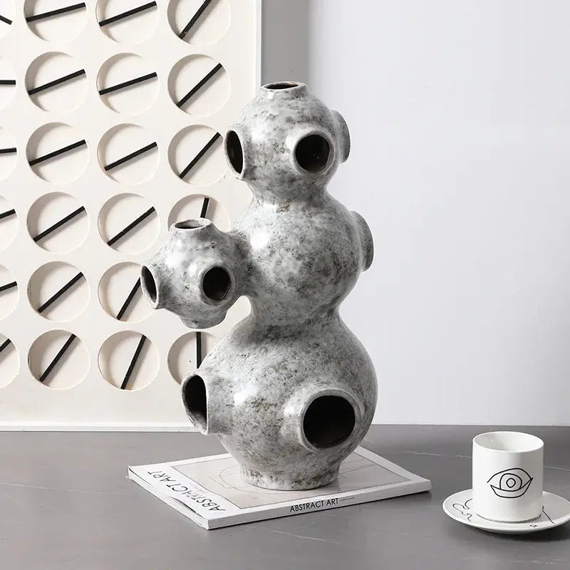 Gray speckled ceramic ornament with rounded segments and circular openings abstract planet decorbites sculpture
