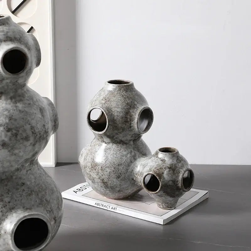 Gray speckled ceramic ornament featuring an abstract planet design with rounded segmented forms and circular openings