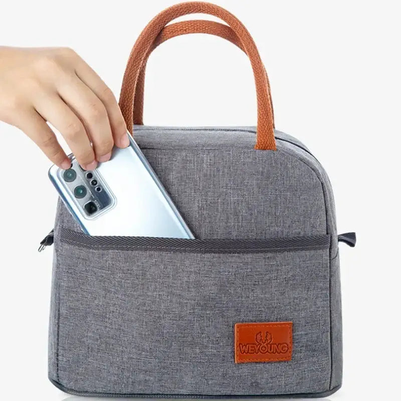 Gray textured insulated lunch bag with brown leather handles and brand patch designed for kitchen thermal use